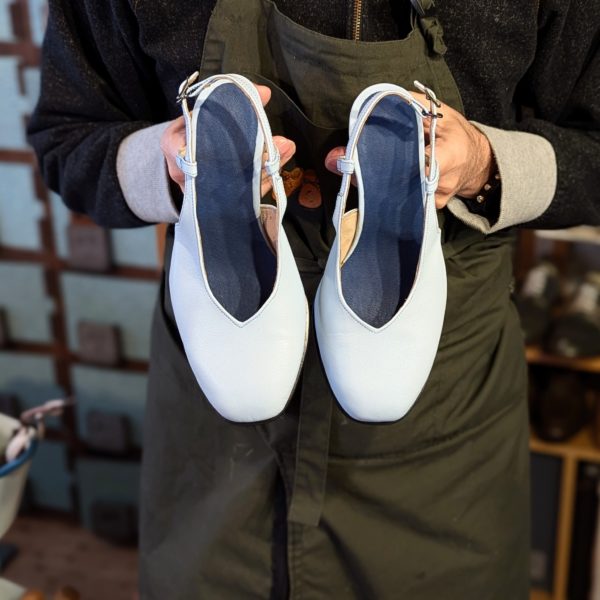 完成した水色のバックストラップパンプスを両手で持っている写真。