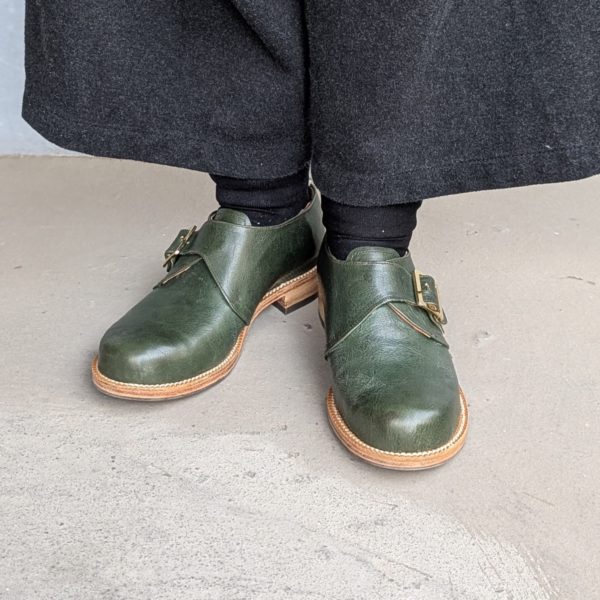 自分の足に合わせて作ったグリーンの革靴を履いた正面写真
